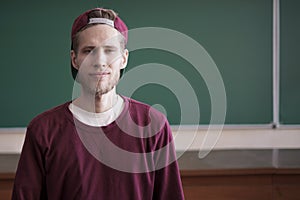 Cool young hipster student in snapback cap casual in university with blackboard on background