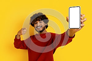 Cool young indian guy pointing at phone in his hand