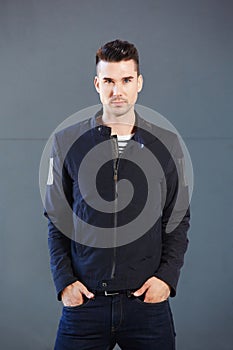 Cool young male fashion model standing against gray background