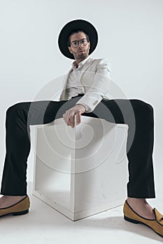 cool young man with hat and glasses sitting on white wooden table