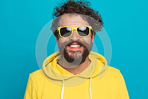 Cool young man in yellow hoodie wearing sunglasses and smiling