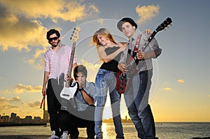 Cool young musical band posing at sunset