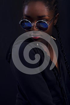 Cool young woman with dark skin wearing round sunglasses