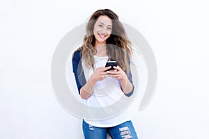 Cool young woman smiling with mobil phone against white background