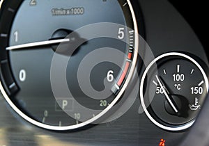 Coolant temperature gauge and tahometer on a car`s dashboard. Car interior details. Close up view.