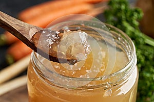 Cooled down congealed beef bone broth on a wooden spoon