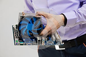 Cooler and motherboard in men`s hands close-up isolated on light background