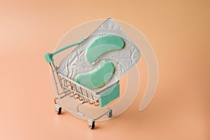 Cooling eye patches in a shopping cart on a beige background