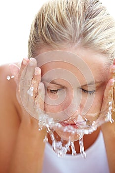 Cooling off. A beautiful young woman washing her face with water.