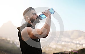 Cooling off after an intense workout. a sporty young man drinking water while exercising outdoors.