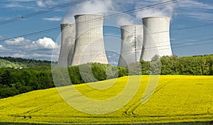 Cooling towers of nuclear power plant with the yellow field of rapeseed, canola or colza. Mochovce. Slovakia