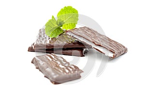 Cooling treat and fattening sweets concept with chocolate pieces with vivid image of refreshing mint filling and spearmint leaves