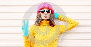 Cooll funny girl blowing red lips wearing colorful knitted yellow sweater pink hat
