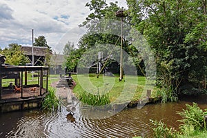 A coop, storks nest, wooden boat and water mill in the yard of a