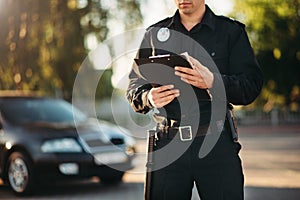 Cop with notebook in hands check the car