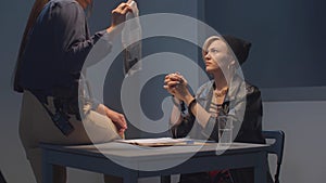 A cop shows a woman a gun as evidence. View