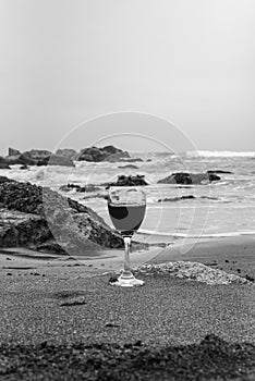 Copa de vino tinto en la playa de arena blanco y negro