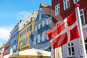 Copenhagen iconic view. Denmark flag against Nyhavn canal with colorful medieval houses in the center of Copenhagen, Denmark