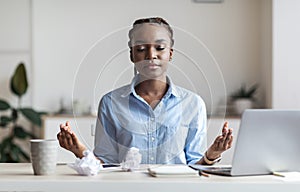 Coping With Stress At Work. Young African Businesswoman Meditating In Office