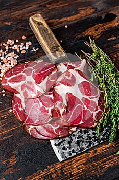 Coppa, Capocollo, Capicollo Cured ham on meat cleaver. Dark wooden background. Top view