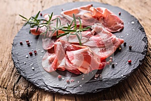 Coppa di Parma ham on slate board with rosemary salt and pepper photo