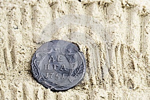 Copper coin in the sand with the inscription Denga 1751 release, old Russian copper coins