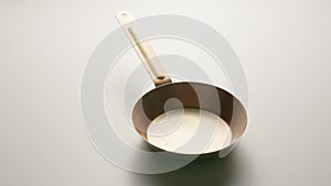 Copper fryingpan spinning on on a light gray studio background. Round empty stainless or aluminum pan with handle