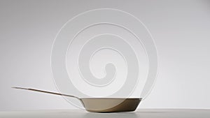 Copper fryingpan spinning on on a light gray studio background. Round empty stainless or aluminum pan with handle