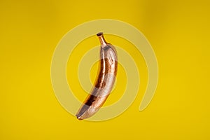 Copper gold floating banana on yellow background. Minimal food concept