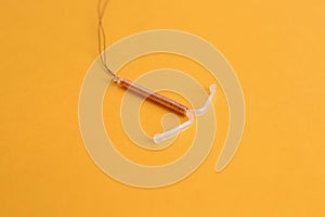 Copper intrauterine contraceptive device on yellow background