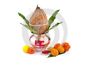 Copper Kalash with coconut, mango leaf, Haldi, kumkum and sweets with marigold flower decoration on a white background.