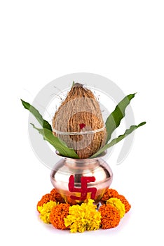 Copper Kalash with coconut and mango leaf and pooja thali with diya, kumkum and sweets with floral decoration on a white
