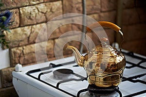 Copper kettle stands on an old vintage plate. Kitchen interior