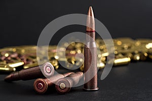 Copper machine gun bullets, more blurred yellow ammo on black board background