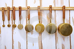 Copper measuring cups with wooden handles hang on the wall in the kitchen