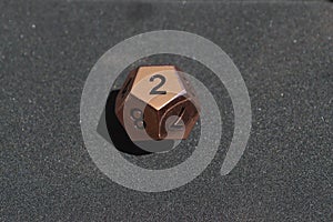 Copper metallic d12 twelve sided dice on foam surface