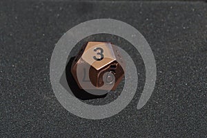 Copper metallic d12 twelve sided dice on foam surface