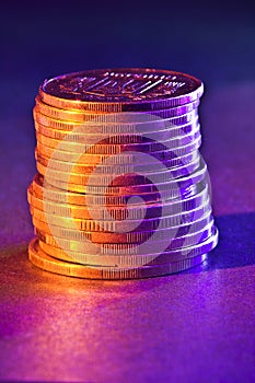 A stack of copper coins with colored lighting close-up
