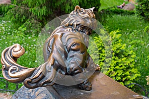 A copper monument to a large, pushy cat looking back