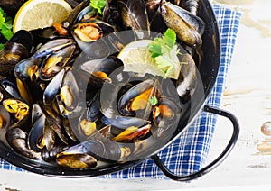 Copper pot of gourmet mussels garnished with lemon slices.