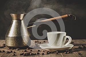 copper pot, hot cup and coffee beans/copper pot, hot cup and coffee beans on a wooden table with dark background.