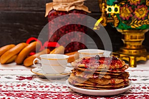 Copper samovar with a traditional pattern. next to pancakes. Russian tea ceremony. two cups on a folk tablecloth