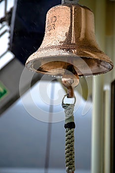Copper ship bell adorned with raindrops: a vintage symbol of maritime tradition, echoing nautical charm