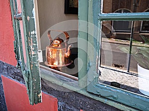 Copper tea pot kettle in a window of an old house