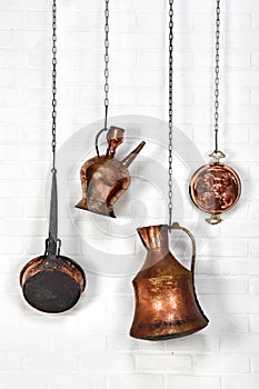 Copper ware hanged on white brick wall photo