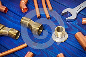 Copper water pipe fittings and a tool for soldering plumbing concept or repair watersupply on vintage blue wooden boards