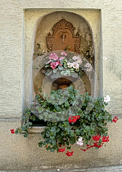 Copper Water spigot and bowl planted with lovely flowers in a niche in a wall, Krems, Austria