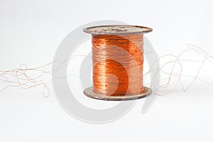 Copper wire spool. Red insulated wire wound up on plastic spindle. End of wire is stripped showing bare copper. Isolated
