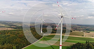 Copter panorama of German nature. Three rotating wind turbines in the golden field surrounded by green forests under