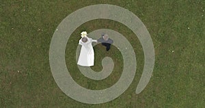 Copter view of wedding. Groom and bride walking though thw big park surrounded by forest